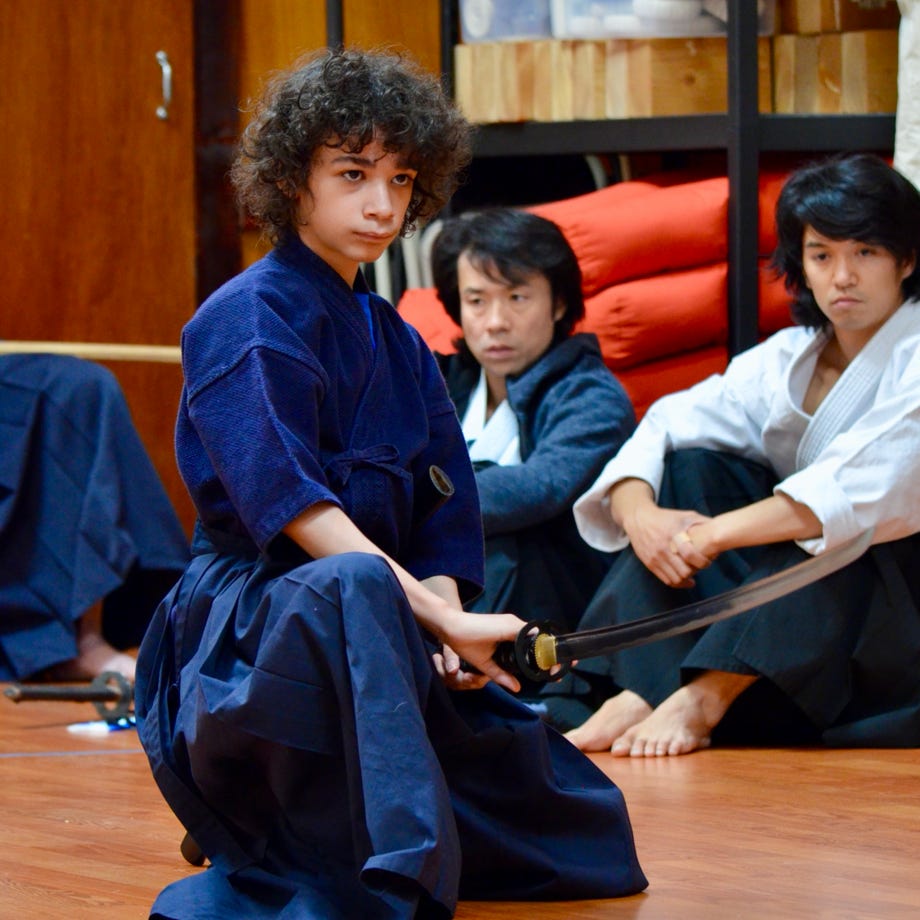 A young girl practicing martial arts indoors, showcasing concentration in her gi.