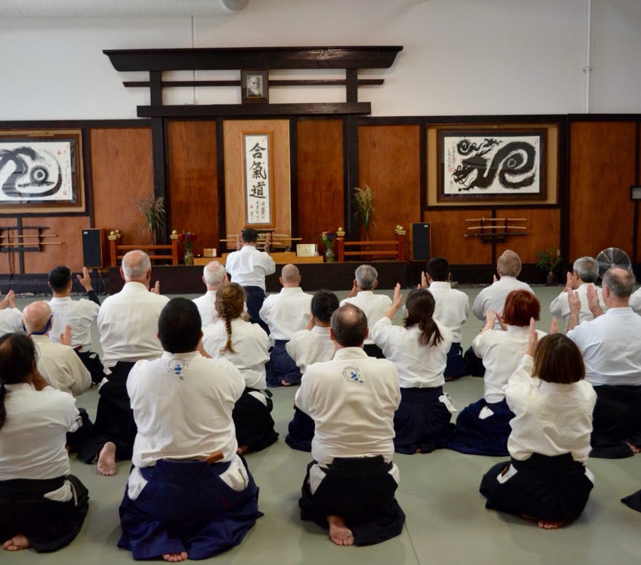 Martial arts instructor demonstrating techniques to young students in a dojo setting.