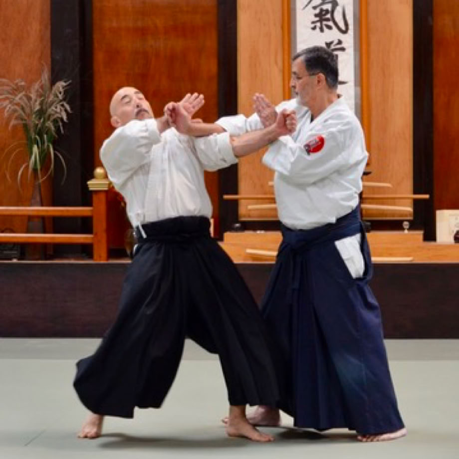 Black and white photo of two men practicing martial arts indoors with natural light.